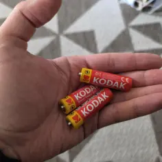 Dwie baterie Kodak w dłoni. Chcesz wiedzieć, jak sprawdzić miernikiem czy bateria jest dobra?