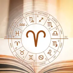 Zodiakalny baran i lew – ich związek bywa burzliwy, ale pełen pasji. Koło zodiaku na tle otwartej księgi.