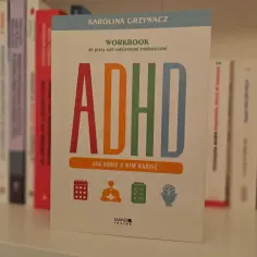 Książka "ADHD. Jak sobie z nim radzić" Karoliny Grzywacz, workbook do pracy nad codziennymi trudnościami. Na okładce kolorowe litery ADHD i ikony symbolizujące organizację, spokój, zadania i umysł.