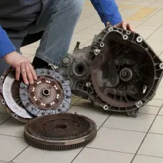 Mechanik pokazuje rozłożony zestaw sprzęgła. Zepsute łożysko oporowe sprzęgła objawy mogą być różne, np. hałas przy wciskaniu pedału.