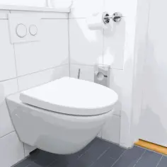Nowoczesna łazienka z podwieszanym WC. Widoczny jest przycisk spłuczki, rolka papieru toaletowego i dyskretny odpływ WC w podłodze.