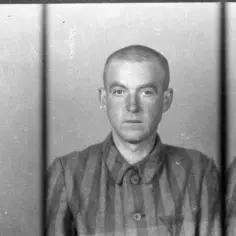 Trzech więźniów obozu Auschwitz, w tym jeden z tabliczką "Pol. 31", w pasiastych ubraniach. Jeden z nich, jakby zapamiętał historie, które chciałby opowiedzieć jako pisarz.