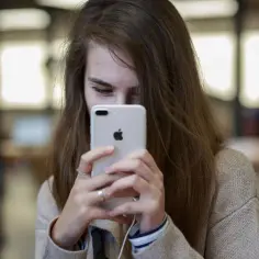 Dziewczyna trzyma iPhone'a, patrząc na ekran.