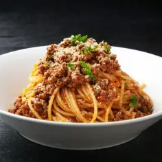 Spaghetti z sosem bolognese, posypane parmezanem i natką pietruszki.