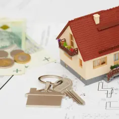 Model domu, klucze, pieniądze i plany architektoniczne symbolizują kosztorys inwestorski.