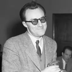 Andrzej Munk, twórca kultowych **andrzej munk filmy**, w okularach i tweedowej marynarce, trzymający coś w dłoni.