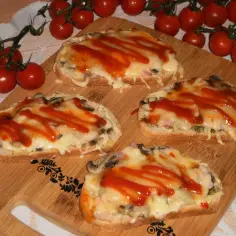 Cztery zapiekane kanapki z serem, pieczarkami i keczupem na desce do krojenia.