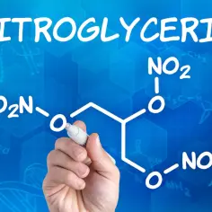 Rysunek przedstawia wzór chemiczny nitrogliceryny, pisany markerem na niebieskim tle z siatką i innymi wzorami chemicznymi.