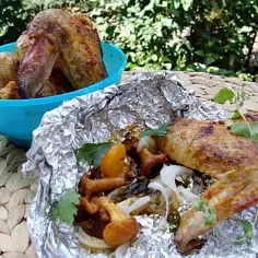 Pyszne kurki na grillu z dodatkiem warzyw, podane na folii aluminiowej i w niebieskiej misce.