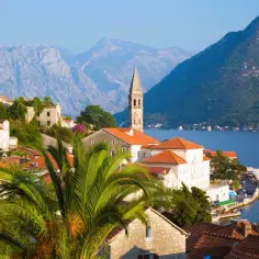 Perast, Czarnogóra – jedno z najpiękniejszych miejsc w Europie. Białe domy z czerwonymi dachami, palmy i góry nad błękitną zatoką.