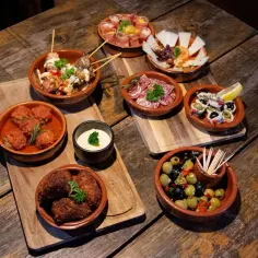 Pyszne hiszpańskie jedzenie: tapas, oliwki, ser i mięsne kulki na drewnianym stole.