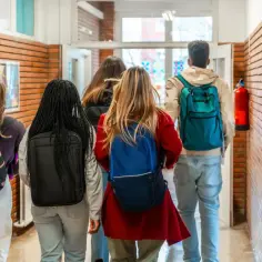 Uczniowie wchodzą do szkoły, zastanawiając się, jakie są licea. Korytarz szkolny z ceglanymi ścianami i kolorowymi obrazami.