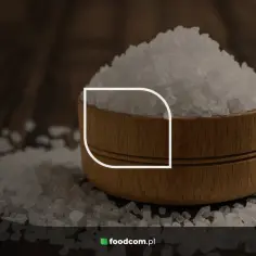 Górka kryształków soli, czyli chlorku sodu, w drewnianej miseczce na ciemnym tle.