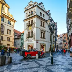Uliczka w Pradze z zabytkowym czerwonym kabrioletem i budynkiem "Złota Uliczka Praga".