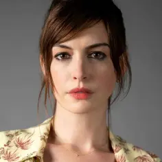 Aktorka amerykańska Anne Hathaway z burzą brązowych włosów i w bluzce w tropikalne wzory.