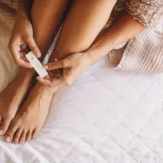 Kobieta trzyma test ciążowy, zastanawiając się, czy przed okresem są dni płodne.