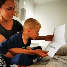 Mama czyta dziecku w przedszkolu bajkę o rycerzu.