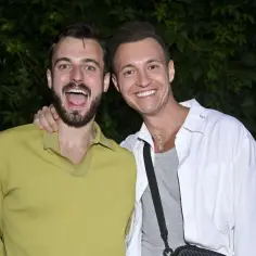 Uśmiechnięci mężczyźni, jeden z nich to Kamil Krupicz, partner, pozują do zdjęcia na tle zieleni.