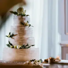 Elegancki tort piętrowy z kremowymi rozetami i kwiatami, idealny na uroczystość. Jak przewieźć tort piętrowy? Ostrożnie!