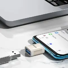 Adapter do pendrive'a podłączony do telefonu, obok laptopa. Tak łatwo znajdziesz pendrive na komputerze.