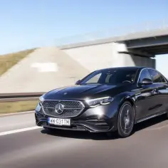 Elegancki, czarny Mercedes E220d mknie autostradą pod błękitnym niebem.