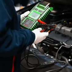 Mechanik w białych rękawiczkach używa testera Bosch do sprawdzenia wtryski w dieslu.