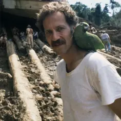 Werner Herzog z papugą na ramieniu, w tle budowa w dżungli, jak w jego filmach.