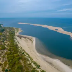Piękne, piaszczyste **miejscowości nad morzem** z zielonymi wydmami i błękitną wodą.