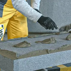 Osoba w żółtym ubraniu pokazuje, jak nakładać klej na styropian, tworząc obwod i placki.