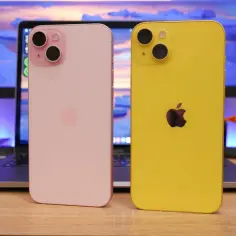 Dwa iPhone'y 15, różowy i żółty, obok laptopa. Zastanawiasz się, ile cm ma iPhone 15?