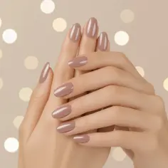 Dłonie z idealnym, beżowym manicure. Paznokcie do opuszka, zadbane i lśniące, na tle rozmytych światełek.