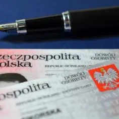 Polskie dowody osobiste, w tym ważny dowód dziecka, leżą obok eleganckiego pióra.