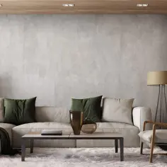 Nowoczesna aranżacja ściany w salonie: beton, drewno, jasna sofa, zielone poduszki i designerski fotel tworzą przytulną przestrzeń.