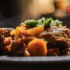 Pyszne, parujące ossobuco wołowe z warzywami na talerzu. Aromatyczne danie, które rozpływa się w ustach.