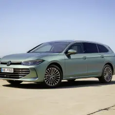 Nowy Volkswagen Passat B9 w kolorze zielonym, zaparkowany na betonowej nawierzchni, z błękitnym niebem w tle.