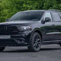 Czarny Dodge Durango na tle zieleni. Wiele osób szuka pozytywnych dodge durango opinie, ten SUV wygląda imponująco.