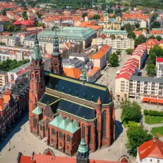 Widok z lotu ptaka na Legnicę, z dominującą katedrą. W tle budynki mieszkalne, które mogą wpływać na ceny mieszkań Legnica.