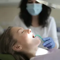 Pacjentka w gabinecie stomatologicznym, dentysta wykonuje zabieg.