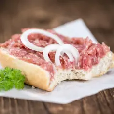 Kanapka z mielonym mięsem, cebulą i natką pietruszki na papierze do pieczenia.