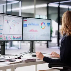 Kobieta analizuje dane na dwóch monitorach. Chcesz wiedzieć, jak sprawdzić parametry monitora?