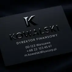Elegancka, czarna wizytówka z wypukłym logo "K" i nazwiskiem Kowalski. Dyskretnie informuje, ile kosztują wizytówki premium.