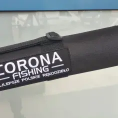 Czarny pokrowiec na wędkę z napisem "CORONA FISHING - NAJLEPSZE POLSKIE RĘKODZIEŁO". Wygląda jak bazuka dla wędkarza.