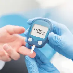 Rękawiczki medyczne i glukometr pokazują wynik 105 mg/dL. Badanie glukozy jest kluczowe dla zdrowia.