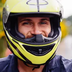 Uśmiechnięty mężczyzna w żółtym kasku motocyklowym. Dobór odpowiednich rozmiarów kasków motocyklowych to klucz do bezpieczeństwa.