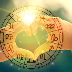 Dłonie tworzą serce na tle koła zodiaku. Widać symbole **bliźniąt** i **panny**, a także inne znaki.