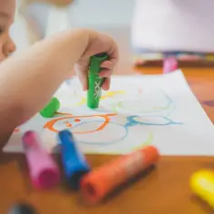 Małe dziecko maluje kredkami. Czy przedszkole jest obowiązkowe? Ta kreatywna zabawa to początek edukacji.