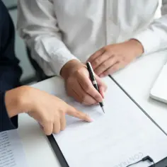 Dwie osoby przy biurku analizują umowę. Jedna wskazuje palcem na dokument, druga podpisuje. Czy pracodawca może zmienić godziny pracy bez zgody pracownika?