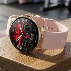 Złoty smartwatch z różową opaską na drewnianym blacie.