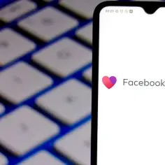 Ekran telefonu z logo Facebook Dating na tle klawiatury.