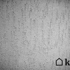 Szara ściana z fakturą tynku kornik, imitującą ślady po żerowaniu owadów. Widoczne pionowe, nieregularne zagłębienia i wypukłości.